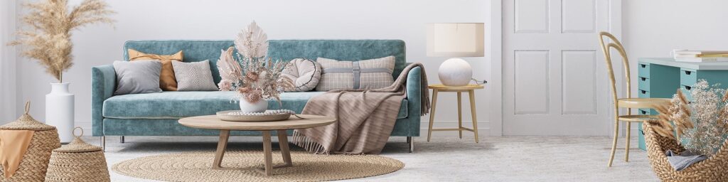 Boho-style living room with a teal sofa, round coffee table, dried floral arrangements, and neutral decor.